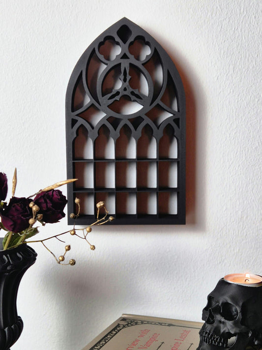 May include: Black wooden gothic window frame wall decor with a pointed arch and intricate details. The frame is mounted on a white wall.